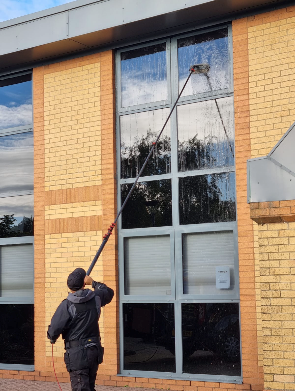 Reach and wash pole cleaning a full height glazed commercial frontage