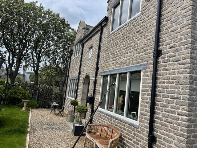 Cleaning the windows of a stone house with a reach and wash pole