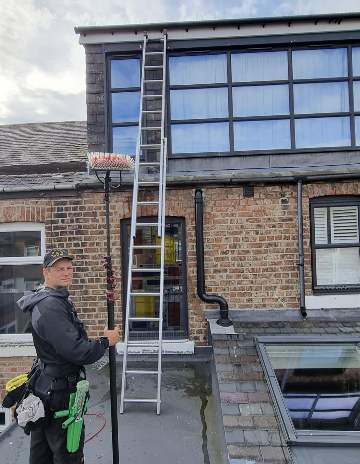 A Rob Gibson cleaner with a water fed pole and ladder on a roof